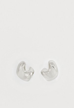 Brincos de metal prateado com um design suave e curvo. Acabamento brilhante, apresentando duas formas assimétricas que se fecham parcialmente.