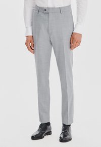 Jasnoszare spodnie wykonane z teksturowanej tkaniny, charakteryzujące się dopasowanym krojem, bocznymi kieszeniami i pojedynczym zapięciem na guzik. W połączeniu z czarnymi butami eleganckimi.