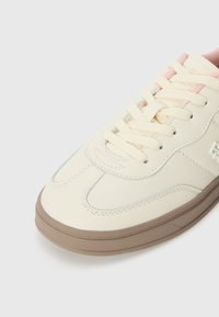 Sneaker beige con finitura in pelle liscia, punta arrotondata, lacci crema, suola in gomma color tan e dettagli di cucitura delicati in azzurro.