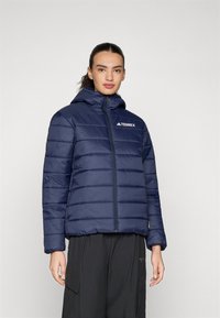 Dunkelblauer Pufferjacke mit durchgehendem Reißverschluss und Kapuze, ausgestattet mit horizontalem Steppmuster und TERREX-Logo auf der Brust. Glatte Textur.