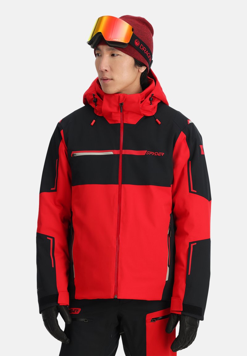 Rote und schwarze Skijacke mit durchgehendem Reißverschluss, verstellbarer Kapuze und kontrastierenden Farbblöcken. Verfügt über reflektierende Akzente und verstärkte Bündchen.