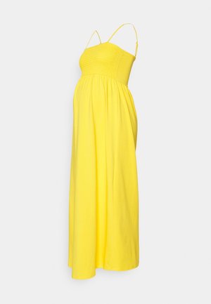 Robe de maternité jaune vif sans manches avec corsage froncé et bretelles spaghetti réglables sur fond uni.
