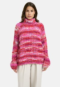 Strickpullover mit hohem Kragen, mehrfarbigen rosa und roten Streifen, lockerer Passform und gerippten Bündchen, die ein strukturiertes Erscheinungsbild erzeugen.