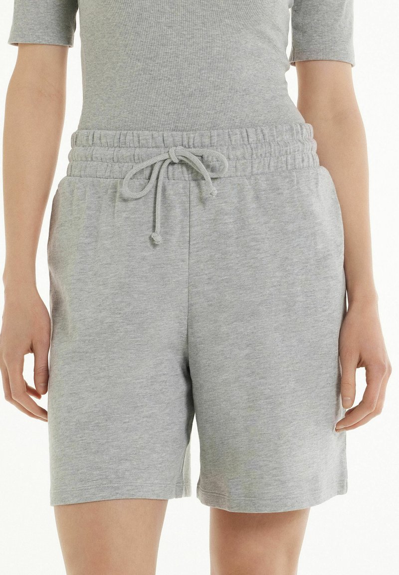 Shorts grigi in cotone con cintura elastica, caratterizzati da chiusura con cordino, taglio fino al ginocchio e una trama morbida e liscia.