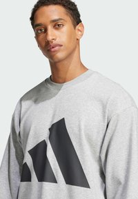 Gray sweatshirt with a black geometric design featuring three stripes. Made of soft fabric with a round neckline and slightly loose fit.