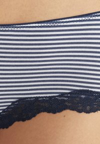 Prugasto donje rublje u tamnoplavoj i bijeloj boji, izrađeno od mekanog materijala s čipkastim detaljem duž donjeg ruba za dodatnu teksturu i stil.