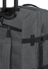 Šedý textilní kufr s teleskopickým madlem, zipovým uzávěrem a nastavitelnými popruhy. Obsahuje strukturovaný povrch a černé kovové akcenty.