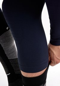 Kniehoog sportcompressiesokken in donkergrijs en zwart, gecombineerd met een marineblauwe elastische legging met gestructureerde patronen en een aansluitend ontwerp.