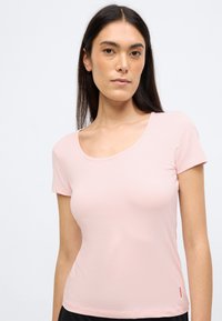 Rózsaszín, rövid ujjú póló sima pamutból. Kerek nyakkivágással és egy kis piros logóval a jobb alsó oldalon.