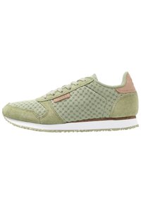 Baskets en mesh vert clair et daim avec des lacets beige, un patch de talon en cuir marron et une semelle blanche avec une accroche texturée.