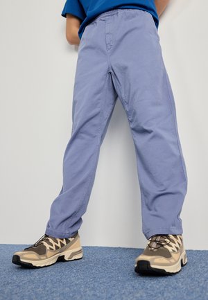Lys lilla bomullsbukser med elastisk midje. Kombinert med beige og svarte joggesko med mesh- og gummidetaljer.