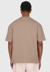 Beige kortærmet t-shirt lavet af blød bomuld, med en afslappet pasform og enkel rund hals. Sømfri konstruktion på bagsiden.