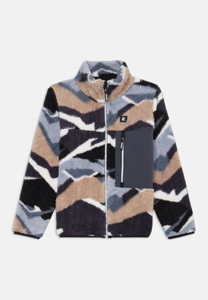 Fleeces jakas ar augstu apkakli, kurai ir daudzkrāsains zigzaga raksts bēšā, melnā, pelēkā un baltā krāsā, ar kabatu uz krūtīm ar rāvējslēdzēju.