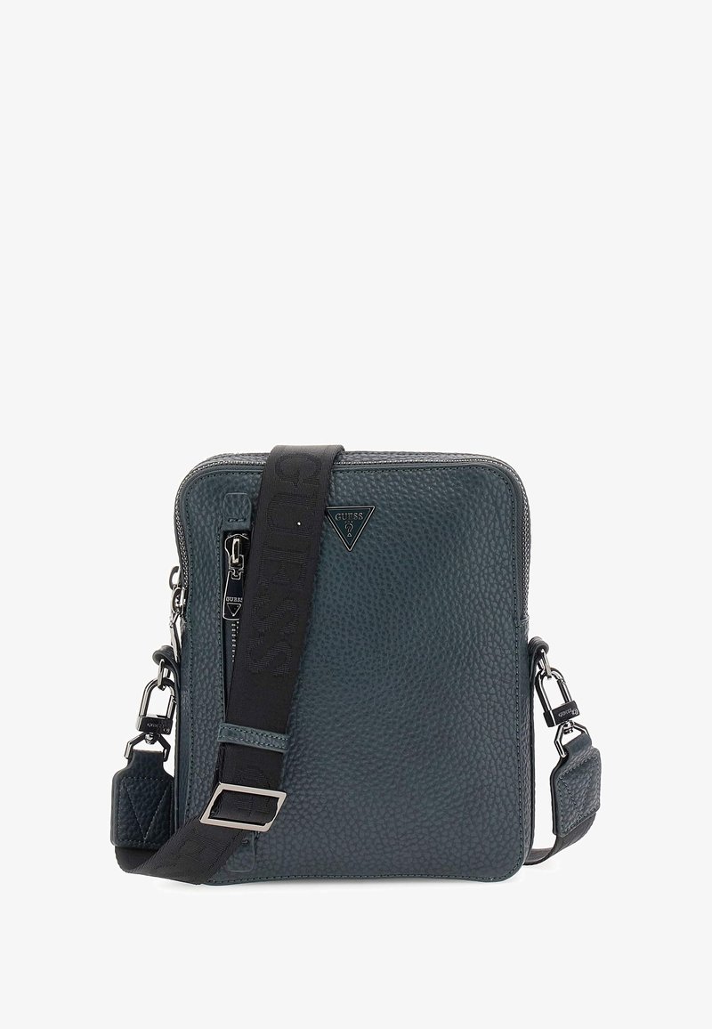 Borsa in pelle quadrata di colore verde scuro con finitura texturizzata, tracolla nera regolabile con nome del marchio e dettagli in hardware argentato.