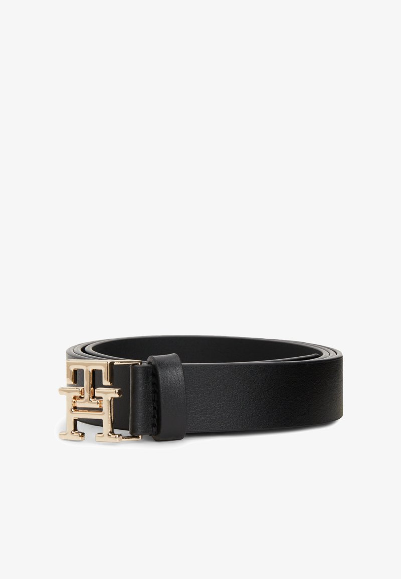 Ceinture en cuir noir roulée avec une boucle dorée en forme de double T sur fond blanc.