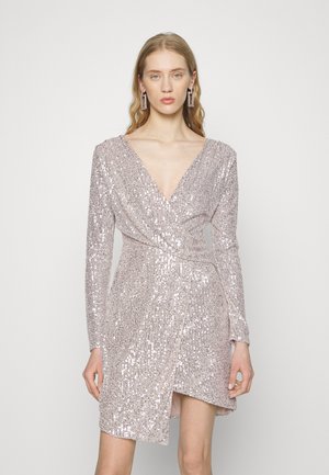 Vestido envelope em tecido rosa claro, adornado com lantejoulas. Manga longa, decote profundo em V e uma fenda até a coxa, apresentando um brilho texturizado.