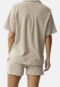 Tan and cream-patterned lounge set featuring a short-sleeve shirt with a collar and matching shorts, both in a herringbone design.