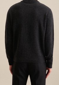 Tummanharmaa neulottu villapaita, jossa on korkea kaulus, resorit hihansuissa ja helmassa. Pehmeä materiaali ja rento istuvuus. Yhdistetty mustiin housuihin.