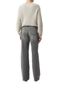Jasnoszary sweter dziany o prążkowanej fakturze, noszony na wysokiej talii, szerokich szarych dżinsach z tylnymi kieszeniami i kontrastowymi szwami.