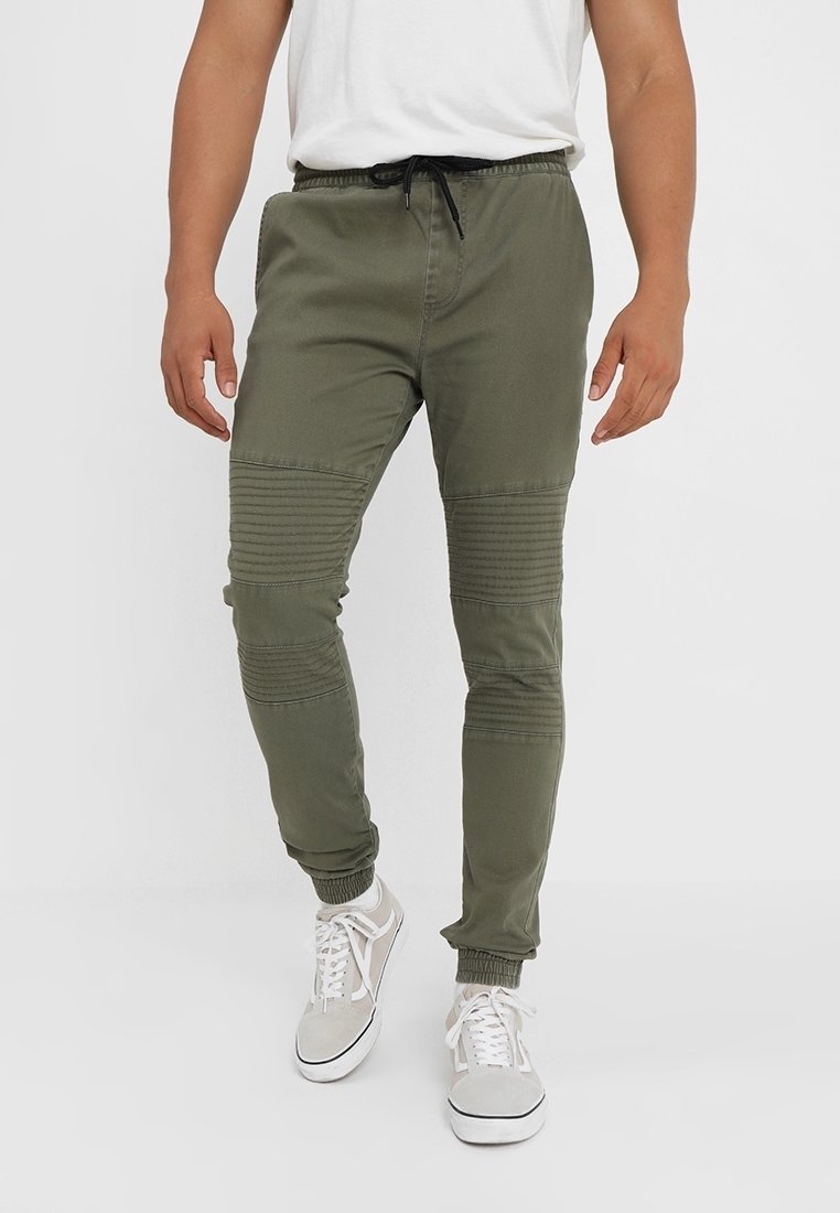 Pantalon de jogging vert olive à coupe fuselée, doté de détails côtelés aux genoux, de poignets élastiques et d'une taille à cordon de serrage.