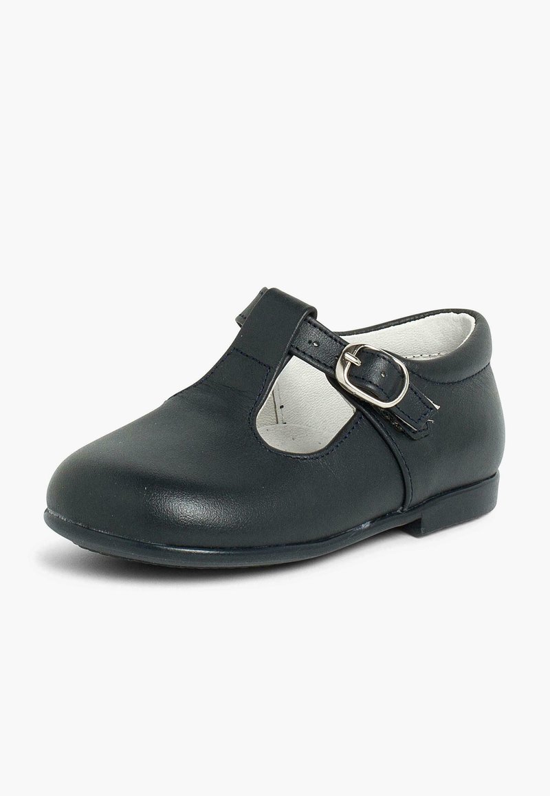 Musthave mustad Mary Jane jalanõud mustast nahast, ümmarguste varvastega, ääre lõikete ja reguleeritava pandlaga. Sile pind ja madal konts.