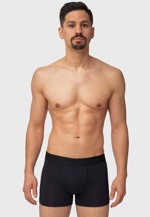 Schwarze Boxershorts aus Baumwolle mit einem dicken elastischen Bündchen, das den Markennamen trägt, in eng anliegender Form und mit glatter Textur.