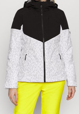 Czarna i biała kurtka z kapturem w panterkę z czarnym zamkiem błyskawicznym i kieszeniami, noszona z jasnymi żółtymi spodniami.