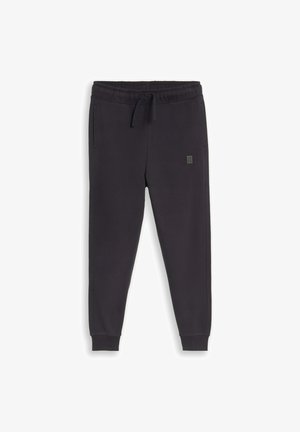 Schwarze Jogginghose mit elastischem Bund, Kordelzug, Seitentaschen, gerippten Bündchen und kleinem rechteckigem Logo am linken Oberschenkel.