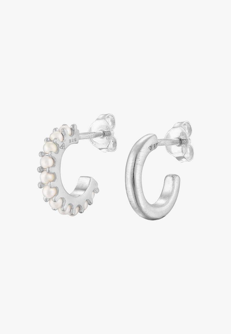 Silverfärgade ringörhängen med texturerad design, den ena med små vita pärlor längs kanten, den andra slät och polerad.