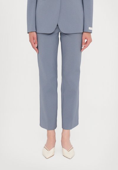 Pantalones ajustados de color azul claro hechos de una tela suave, con un corte slim y piernas rectas, combinados con tacones de punta en crema.