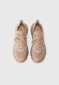 Scarpe da ginnastica beige con pannelli in rete e solidi, superfici testurizzate, punta rotonda, allacciatura frontale e colletto imbottito per comfort.