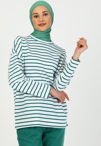Camicia a maniche lunghe in tessuto leggero, con strisce orizzontali alternate verdi e bianche, colletto rotondo e vestibilità comoda.