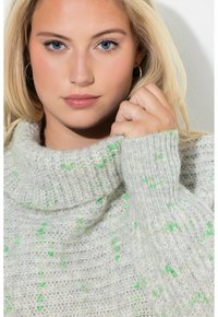Jasnoszara dzianinowa sweter z wysokim kołnierzem, z teksturowanym wzorem i zielonymi plamkami. Miękki, ciepły materiał z prążkowanymi mankietami.