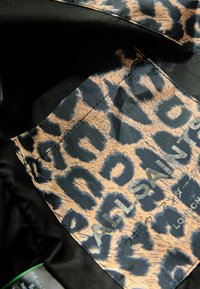 Sort stof med leopardprint-foring i beige og blå nuancer; har et mærke med "ALL SAINTS" trykt i sølv. Struktureret overflade.