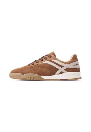 Brązowy zamszowy sneaker z beżowymi i białymi bocznymi paskami, brązowymi sznurowadłami i beżową gumową podeszwą, pokazany z zewnętrznej strony.