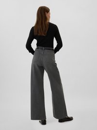 Jean taille haute à jambes larges en denim gris foncé, avec deux poches arrière et une coupe droite, associé à un pull noir ajusté.
