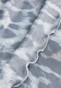 Tessuto grigio texture con un motivo bianco marmorizzato; i bordi presentano un design ondulato, cucito. Qualità leggera e semi-trasparente evidente.