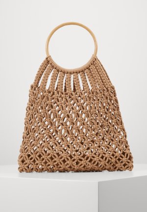 Brown macrame tote bag with circular wooden handles, featuring an open woven floral pattern against a neutral background.
