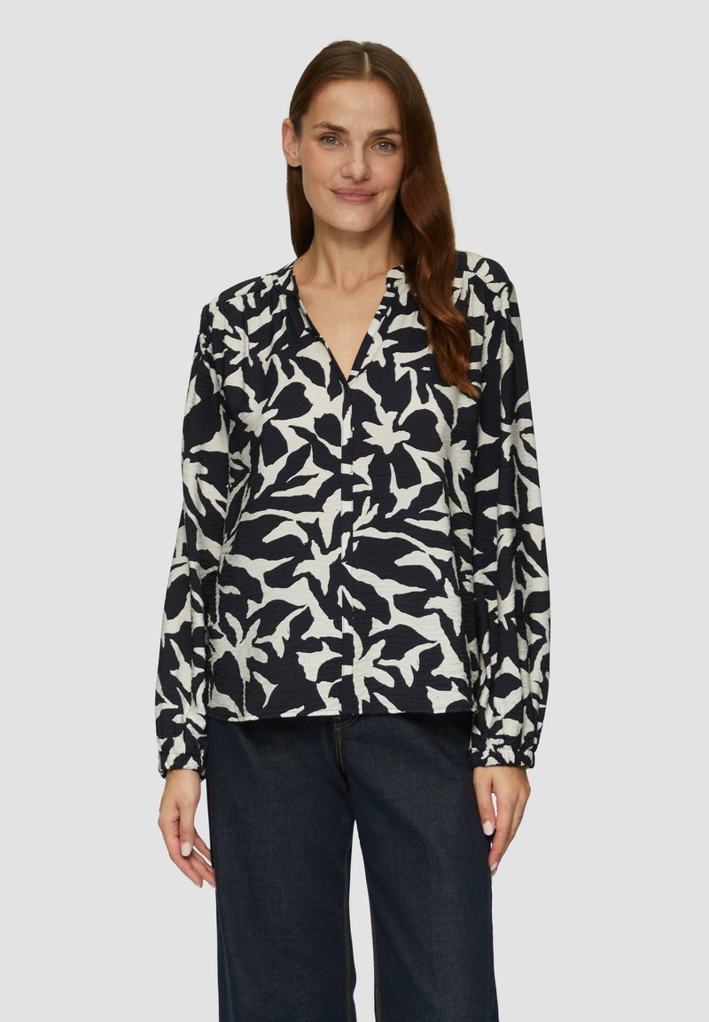 Langärmlige Bluse mit V-Ausschnitt und einem schwarz-weißen botanischen Druck. Hergestellt aus strukturiertem Stoff, mit Raffung an den Schultern.