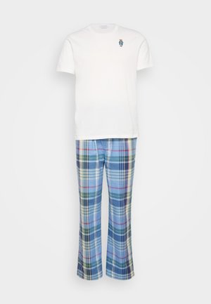 Fehér, rövid ujjú póló kis kék és barna hímzett mintával, kék kockás pizsama nadrággal, amely több színű vonalakkal díszített.