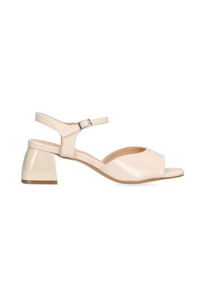Sandalia beige de punta abierta con tacón de charol y una correa en el tobillo, que presenta una textura suave y un diseño curvado.