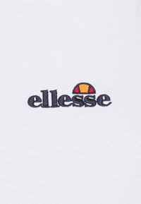 T-shirt en coton blanc avec un logo "ellesse" brodé en noir et un demi-cercle coloré au-dessus en orange et rouge.