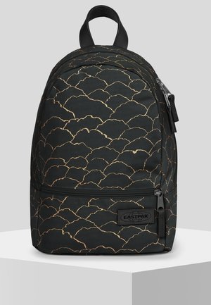 Czarny plecak Eastpak ze złotym wzorem muszli, przednia kieszeń na zamek, górna rączka i naszywka z logo, prezentowany na białej platformie.