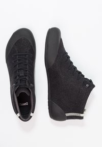 Black high-top shoes with a textured knit upper and smooth rubber toe cap. Features laces and a pull tab at the heel for easy wear.