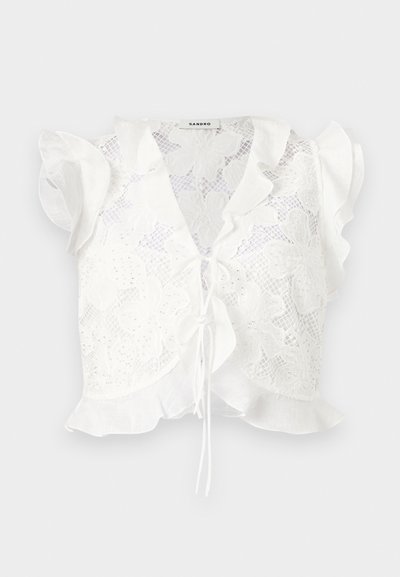 Λευκό δαντελένιο cropped τοπ με λουλουδάτα μοτίβα, κοντά μανίκια με βολάν, κλείσιμο με δέσιμο μπροστά και βολάν στο τελείωμα.