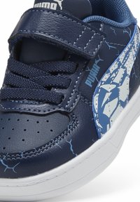 Plave kožne tenisice s bijelim naglascima, teksturirani gornji dio, vezanje i čičak zatvaranje, s geometrijskim uzorkom sa strane.