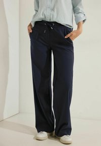 Marina vida byxorna med vida ben av lättviktig tyg, med elastisk midja och snörning samt sidofickor. Matchas med vita sneakers.