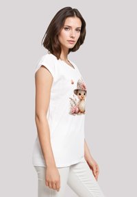 White cotton t-shirt featuring a detailed illustration of a chick with a hat and floral accents, short sleeves, and a relaxed fit.