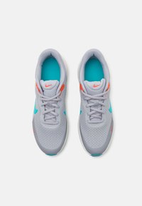 Zapatillas deportivas grises con parte superior de malla, acentos turquesa, detalles naranjas y una suela texturizada. Los cordones son grises y cuentan con una plantilla acolchada.