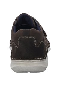 Brown suede shoe with a white rubber sole, featuring visible stitching details and a textured heel tab for easy wear.